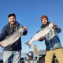 two men holding up fish in their hands