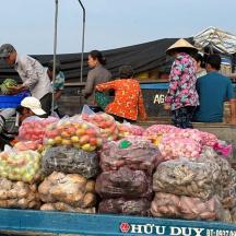 a group of people standing on a boat with produce