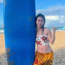 a woman standing next to a blue surfboard on the beach