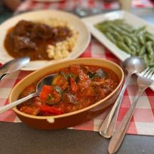 a table with a bowl of food and a plate of green beans