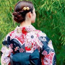 a woman wearing a kimono standing in front of a tree