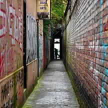 allee, mille telliskiviseina küljel on grafiti