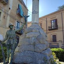 o statuie a unui bărbat care stă în fața unei clădiri