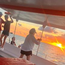 eine Gruppe von Menschen auf einem Boot mit einem auf die Seite gemalten Sonnenuntergang