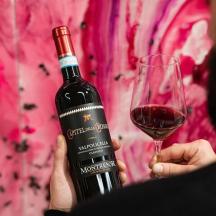 a person holding a bottle of wine and a glass