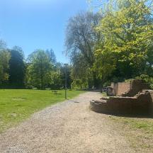 a dirt road in a park with a brick wall