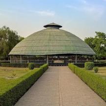 a large building with a green roof in a park