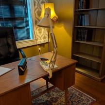 an office with a desk with a lamp and a chair