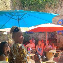 a group of people sitting at a table under a blue umbrella