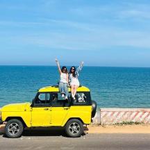 two people sitting on the top of a yellow jeep