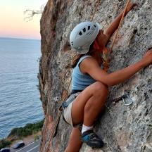 a woman is climbing on a rock near the water