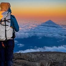 Ein Mann mit einem Rucksack steht auf einem Berggipfel