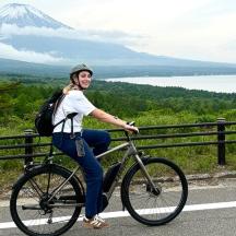 a woman riding a bike on a road with a mountain in the background