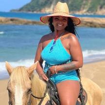 a woman in a straw hat riding a horse on the beach