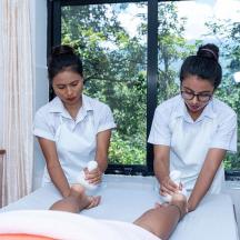 two women scrubbing a mans feet in a bed