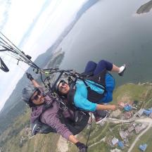 two people hanging from a parachute over a mountain