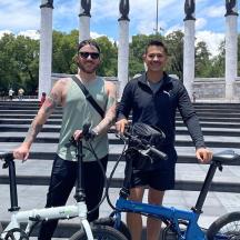 two men standing with their bikes in front of a building