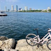 ein Fahrrad, das auf Felsen in der Nähe des Wassers mit einem Boot geparkt ist
