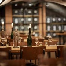 a restaurant with tables with wine bottles and glasses