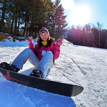 a woman sitting in the snow on a snowboard