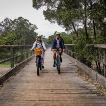 two people riding their bikes on a bridge