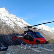 a red helicopter parked in front of a snow covered mountain