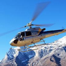 a helicopter flying over a snow covered mountain