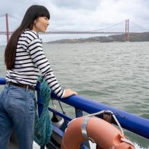 a woman standing on a boat with a bridge in the background