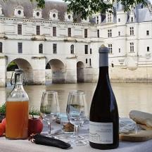 a bottle of wine sitting on a table with wine glasses