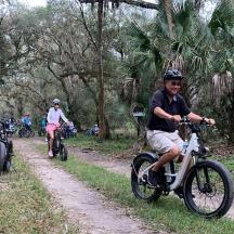 a group of people riding bikes down a dirt road