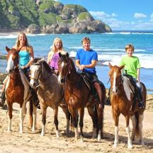 a group of people riding horses on the beach