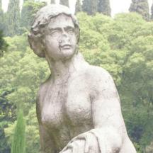 a statue of a woman standing in front of trees