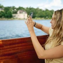 a woman sitting on a boat taking a picture of the water