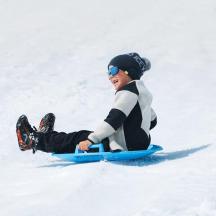 a young boy riding a snowboard down a snow covered slope