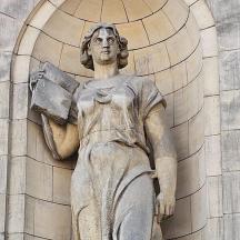 a statue of a woman standing in front of a building