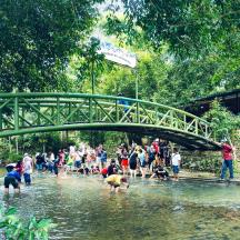 a group of people playing in the water under a bridge