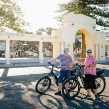 a man and woman standing with their bikes in front of a building