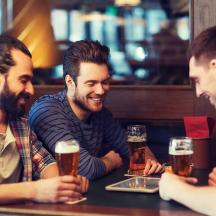 drei Männer sitzen an einem Tisch und trinken Bier