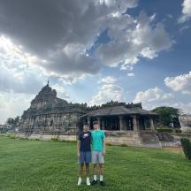 two men standing in a field in front of a building