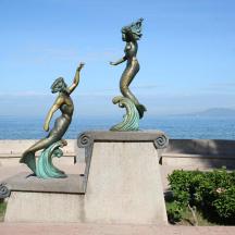 海の近くの壁に置かれた3人の人魚の像