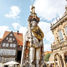 eine Statue mit einer Uhr darauf vor einem Gebäude