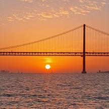 a bridge over the water with the sunset in the background