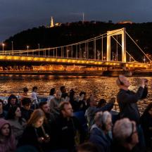 a crowd of people sitting next to a bridge