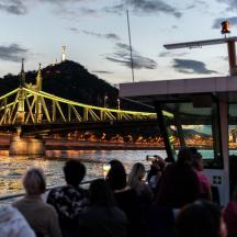 a group of people sitting on a boat looking at a bridge