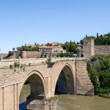 a stone bridge over a river in a city