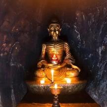 a gold statue with candles in a room