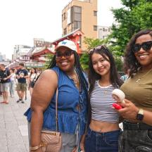 a group of three women standing on a city street