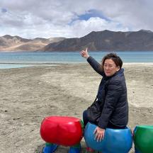 eine Frau sitzt auf einem Spielgerät am Strand
