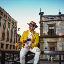 a man in a hat sitting on a fence with a camera