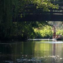 a man standing on a boat in the water under a bridge